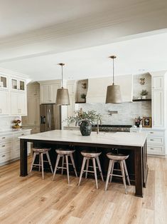 a kitchen island with stools in front of it and lights hanging from the ceiling