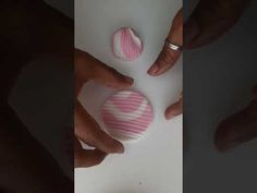 two hands are holding pink and white paper balls