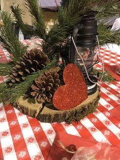 a table topped with pine cones and a heart shaped candle on top of a piece of wood