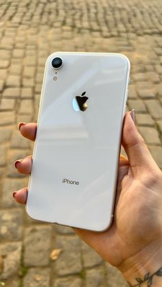 a person holding an iphone in their hand on a cobblestone street with brick pavement