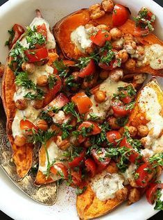 a white plate topped with baked potatoes covered in cheese and veggie toppings