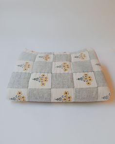 a gray and white checkered dog bed with yellow flowers on the bottom, in front of a white background