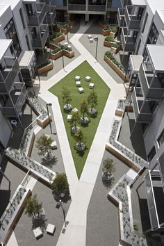 an aerial view of some buildings with grass in the middle and trees on each side