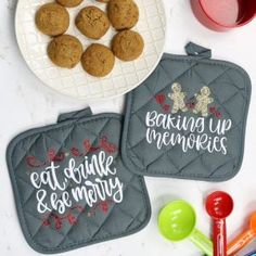 two oven mitts sitting on top of a table next to a plate of cookies