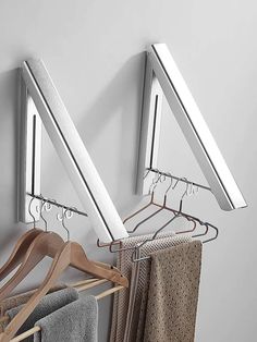 two metal clothes racks with hangers and towels hanging from them on a white wall