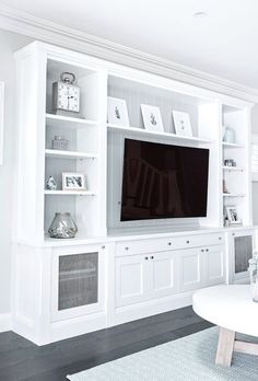 a living room with white bookcases and a flat screen tv on the wall