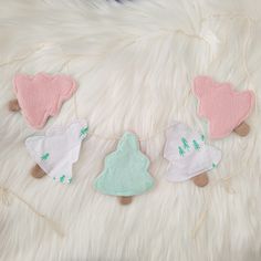 three felt ornaments hanging on a white furnishing with green and pink trimmings