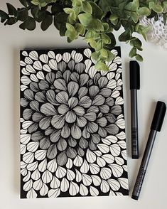 a black and white drawing next to a pen on top of a paper with leaves