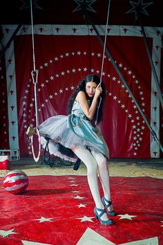 a woman sitting on a swing in front of a red and white star covered stage