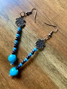 a pair of blue beaded earrings on top of a wooden table