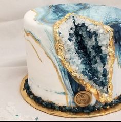 a white and blue marble cake with gold trim