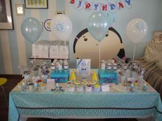 a table topped with balloons and cake next to a blue wall covered in birthday decorations