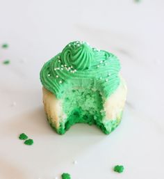 a cupcake with green frosting and sprinkles on it's side