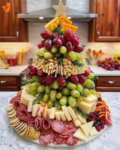 a christmas tree made out of cheese, meats and grapes on a kitchen counter