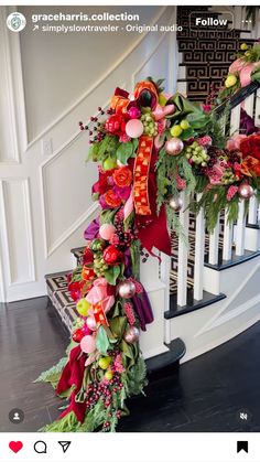 a christmas wreath is on the banister in front of a stair case with red and green decorations