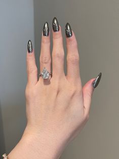 a woman's hand with silver nail polish holding a diamond ring