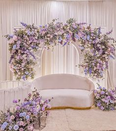 a white couch sitting in front of a flower covered wall with purple flowers on it