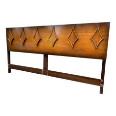 a wooden headboard with metal designs on it's sides and an iron bar at the top