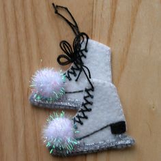 two pairs of white shoes with silver and green sparkles on them sitting on a wooden surface