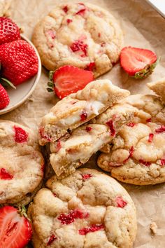 three strawberry cookies with white chocolate chips and strawberries on a plate next to each other