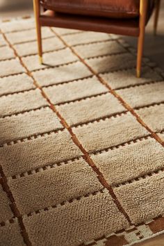 a brown leather chair sitting on top of a wooden floor next to a white rug