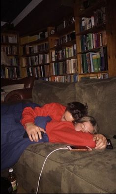 a woman laying on top of a couch next to a book shelf