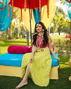 a woman sitting on top of a bed next to an open umbrella in the grass