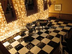 a black and white checkered floor with lights on the walls, chairs and tables