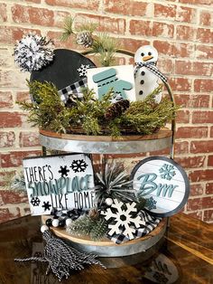 a metal bucket filled with christmas decorations on top of a wooden table next to a brick wall