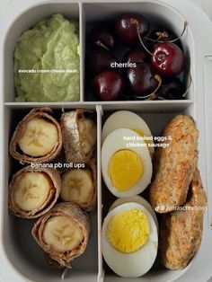 an open lunch box with eggs, fruit and sausage