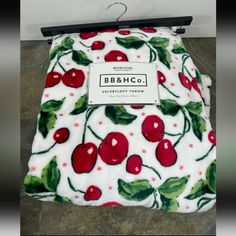 a white blanket with red cherries on it and the name bb & h co