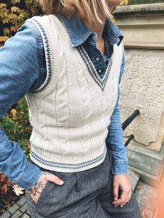 a woman with her hands on her hips wearing a denim shirt and jeans, standing in front of a bench