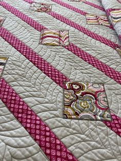 a quilted bedspread with pink and white designs on it's edges