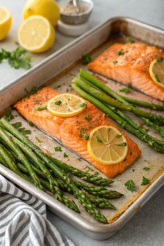 salmon and asparagus on a baking sheet with lemons