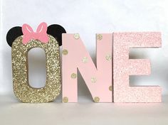 a pink and gold minnie mouse wooden letter that says one