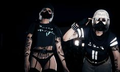 two people wearing masks and bodysuits are standing in front of a dark background