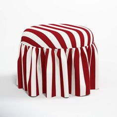 a red and white striped ottoman with ruffles on it's sides, sitting in front of a white background