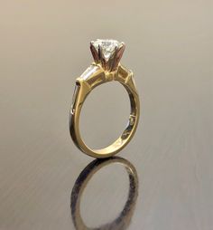 DeKara Designs Collection An Elegant Yellow Gold Diamond Engagement Ring, Modern, Tasteful, Timeless and Affordable. Metal- 18K Yellow Gold, .750. Stone- Center Round Diamond J-K Color SI2 Clarity 1.01 Carats, 2 Baguette Diamonds H Color VS2 Clarity 0.20 Carats. Size- 6. FREE SIZING Beautiful Diamond Engagement Ring Handmade in 18K Yellow Gold. The ring features a fiery round diamond in the center that is professionally set in between six prongs in 18K white gold. There is one channel set baguet Engagement Ring Modern, Wedding Ring Solitaire, Yellow Gold Diamond Engagement Ring, Solitaire Diamond Ring, Gold Diamond Engagement Ring, Handmade Engagement Rings, Gold Diamond Engagement Rings, Diamond Solitaire Ring, Wedding Rings Solitaire