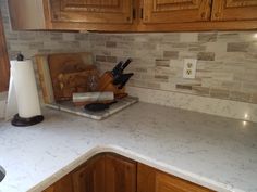 a kitchen counter top with wooden cabinets and marble tile backsplash in the background