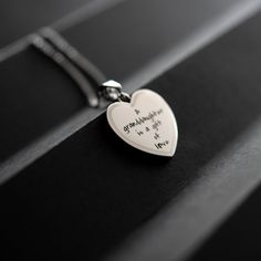 Celebrate the precious bond between a granddaughter and her grandparents with this beautiful heart pendant necklace from Joyful Sentiments. Exquisitely crafted in Stainless Steel, the pendant features the heartfelt engraving "A Granddaughter is a Gift of Love" accented with a shimmering cubic zirconia stone set in the center of the letter "O". The pendant hangs gracefully from an 18 inch Stainless Steel chain with a 3 inch extender, allowing you to adjust the length for the perfect fit. Stainles Mother's Day Heart Charm Locket Necklace Gift For Mom, Mother's Day Heart Locket Necklace With Hallmark, Mother's Day Sterling Silver Locket Necklace Gift For Mom, Mother's Day Gift White Gold Locket Necklace, Mother's Day White Gold Locket Necklace Gift, Meaningful Heart-shaped Keepsake Necklace, Engraved Locket Necklace For Mom For Valentine's Day, Personalized Sterling Silver Locket Necklace For Mom, Mother's Day White Gold Locket Necklace