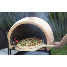 the pizza is being cooked in an outdoor wood fired oven, with one slice taken out