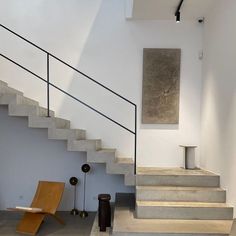 an empty room with some stairs and a painting on the wall next to a chair