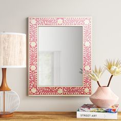 a pink and white mirror sitting on top of a wooden table next to a lamp