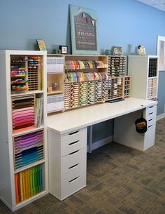 a white desk topped with lots of drawers and shelves filled with different types of fabrics