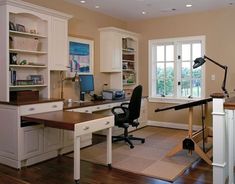 a home office with white cabinets and wood flooring, along with a large window