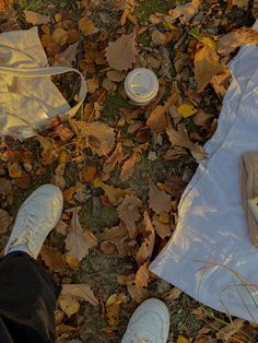 a person standing next to a white bag on top of leaves