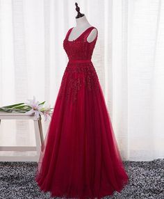 a red evening dress on display in front of a white curtain and flower vases