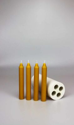 four candles sitting next to each other on top of a white surface with one candle in the middle