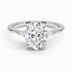 an oval cut diamond ring with three diamonds on the band and side stones set in 18k white gold