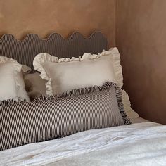 a bed with white and black striped pillows on it's headboard, next to a brown wall